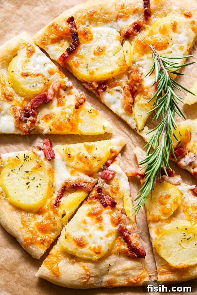 Top down view of a golden-baked potato and pancetta pizza on a rustic wooden board, garnished with fresh rosemary.
