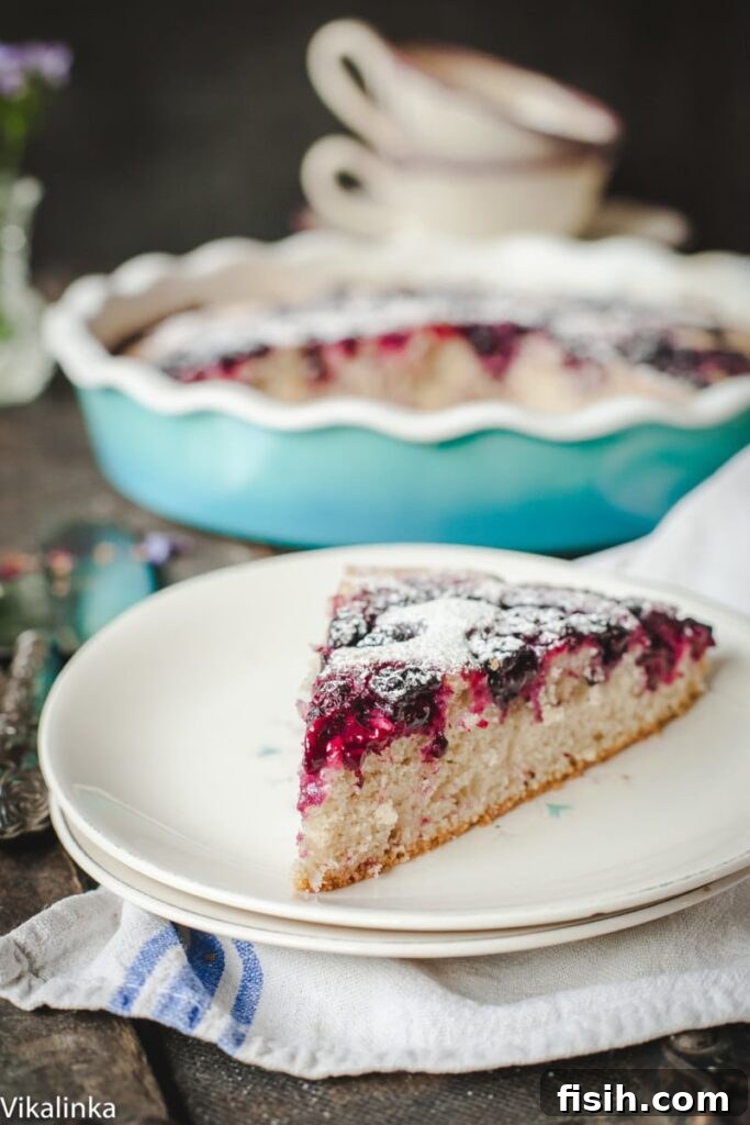 A perfectly baked slice of Wild Blackberry Tea Cake, showcasing its tender crumb and bursts of juicy blackberries, served on a pristine white plate.