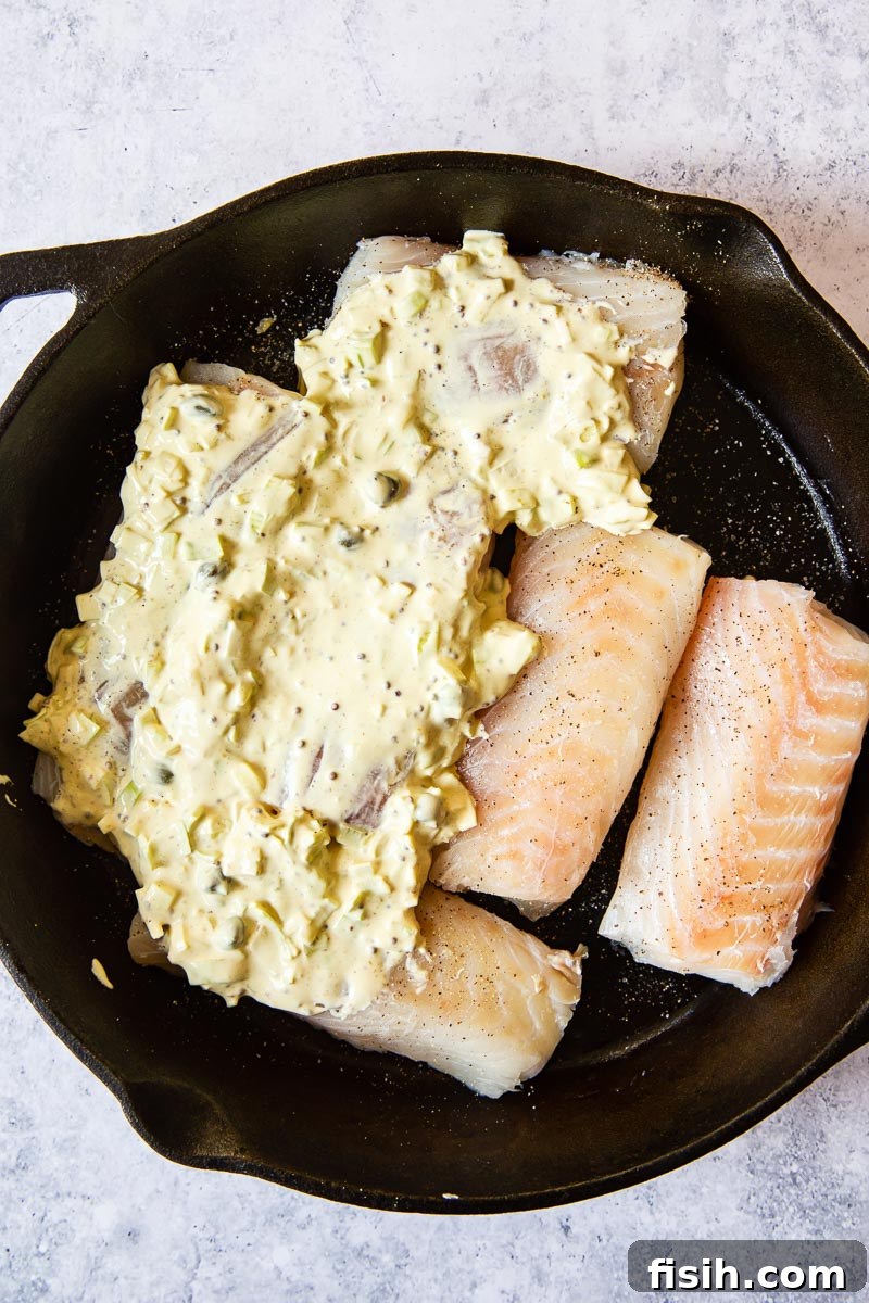 raw cod fillet generously topped with creamy mustard sauce, prepared for baking