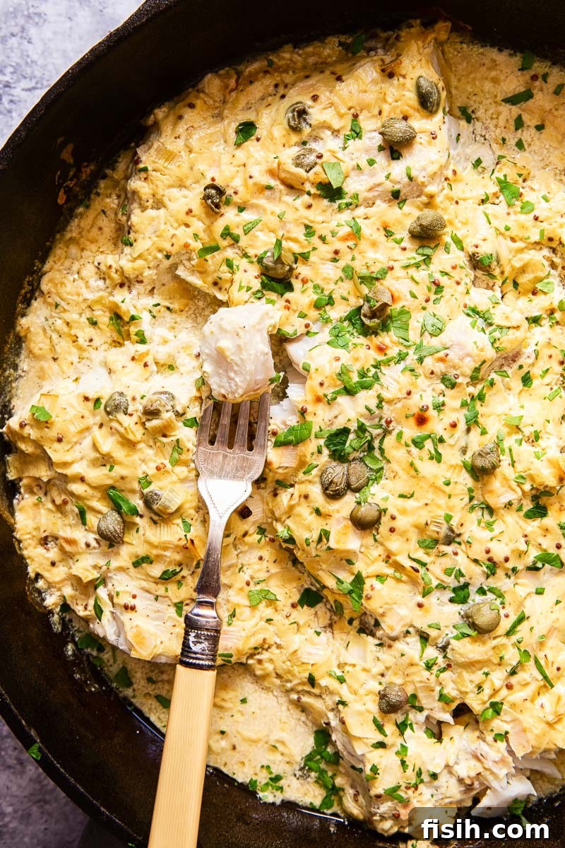 baked fish under a creamy mustard sauce, sprinkled with fresh chopped parsley, in a cast iron skillet