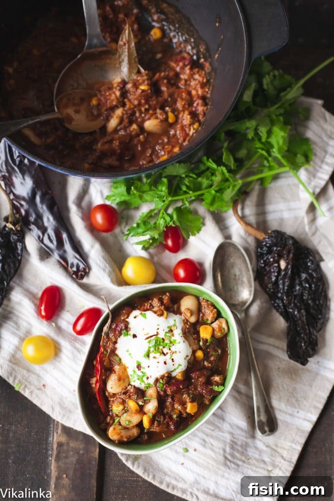 Ultimate Texas Chili 4 Top-down view of a pot and a bowl of rustic Texas-style chili on a wooden table, emphasizing its homemade appeal.