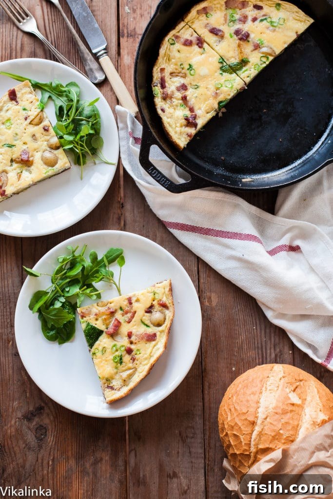 A large skillet holding a golden French Omelette studded with crispy bacon, diced potatoes, and tender zucchini