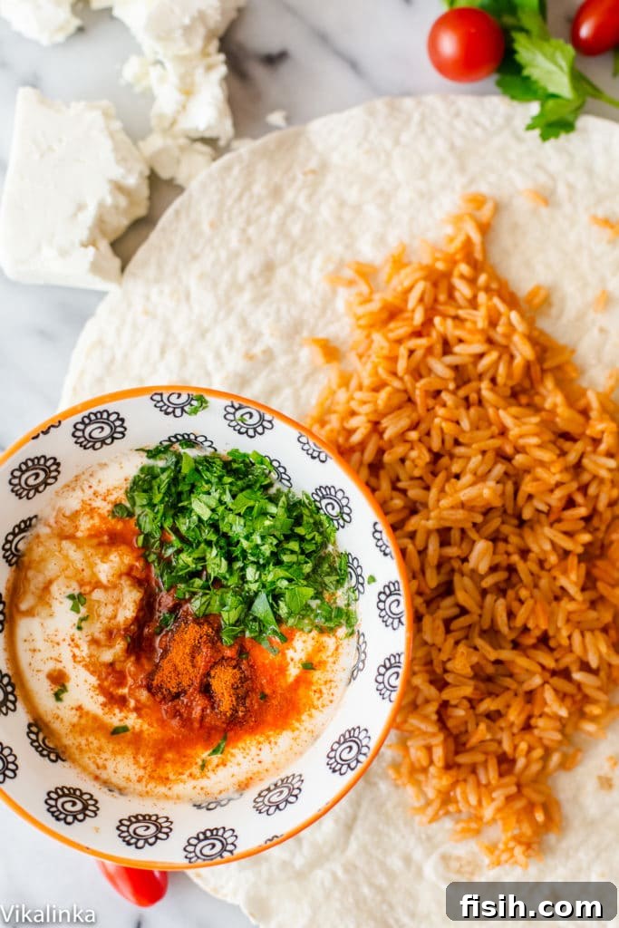 Deconstructed Peri Peri Rice and Chicken Wrap ingredients: rice, chicken, avocado, tomatoes, feta, and the spicy yogurt sauce in a bowl