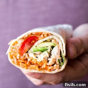 Hand holding peri peri rice and chicken wrap showing cross-section