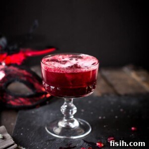 A vibrant red berry cocktail, on a dark grey background, ready to be enjoyed.
