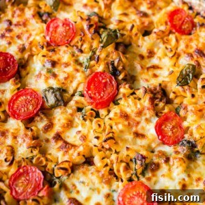 sausage pasta baked with cherry tomatoes on top in round pan