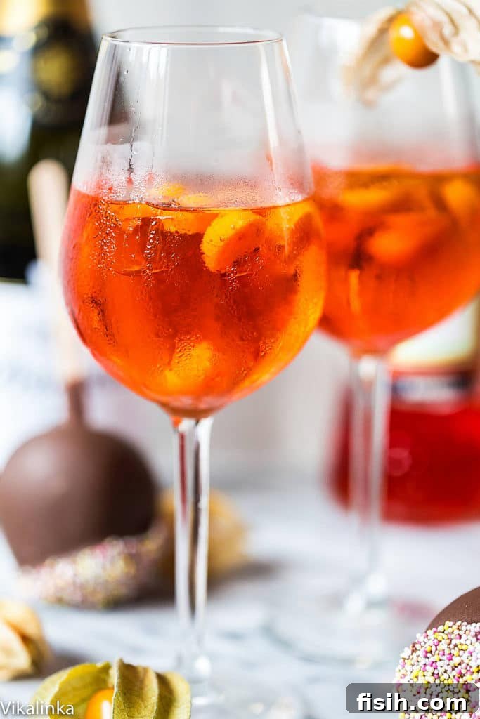 Golden Hour Refresher 3 Close-up of a glass of Aperol Spritz with ice and an orange slice, highlighting its vibrant orange color and refreshing bubbles.