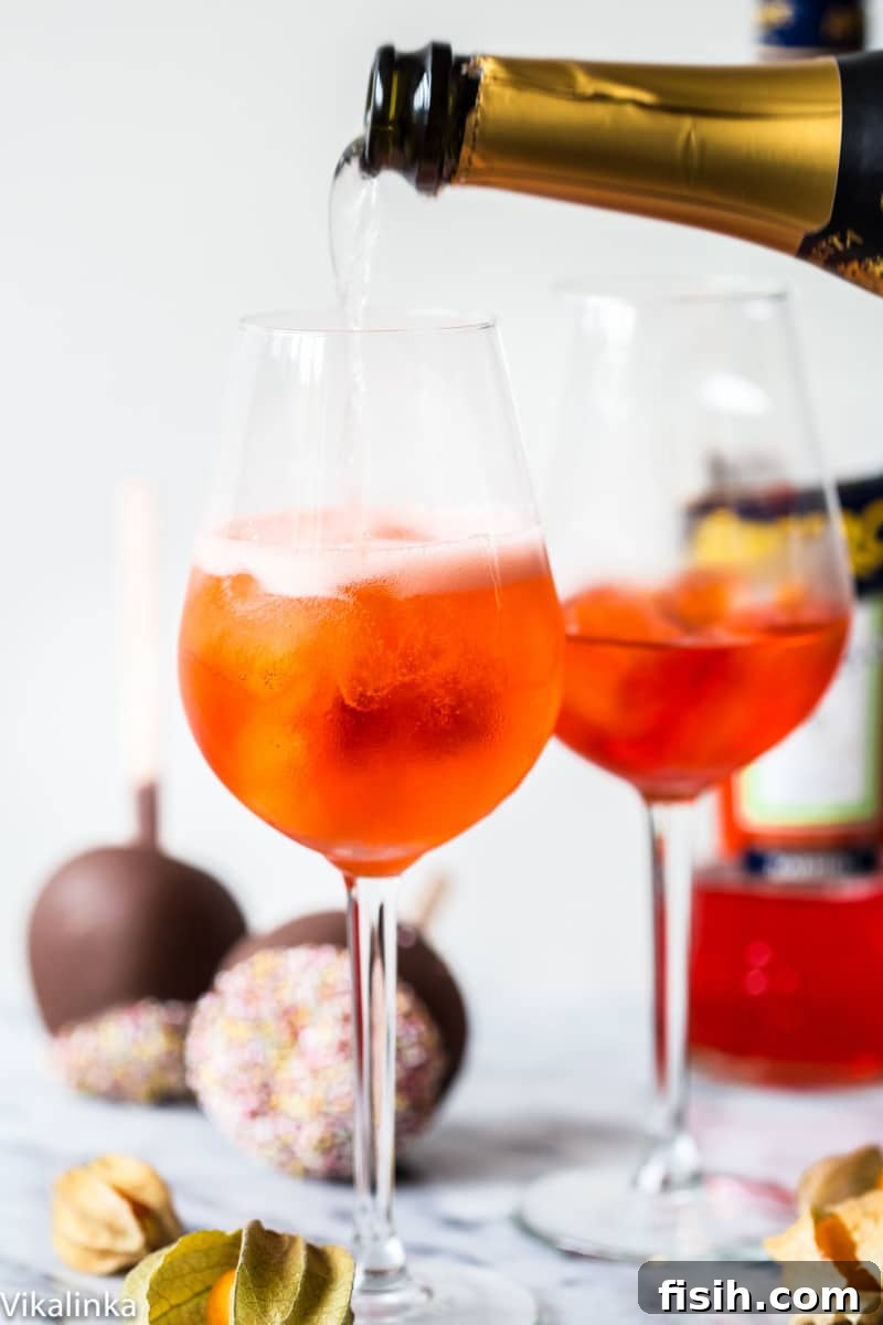 Golden Hour Refresher 4 A bottle of sparkling wine being poured into a large wine glass filled with a vibrant orange drink and ice, illustrating the making of an Aperol Spritz.