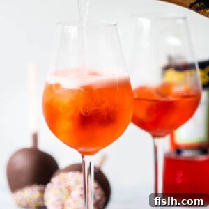 A bottle of sparkling wine being poured into a glass with orange drink, highlighting the Aperol Spritz preparation.