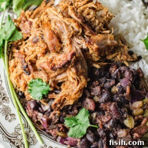 Overhead shot of Slow Cooker Cuban Pork, black beans, and white rice arranged attractively on a plate.