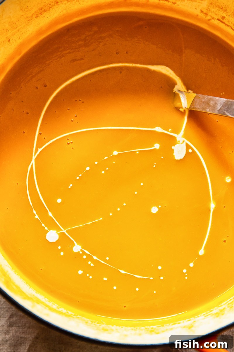 squash soup in a pot with a cream swirl