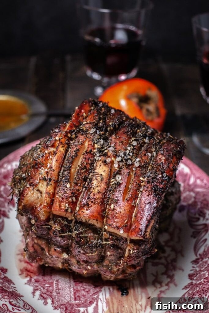 Cooked pork roast on a serving platter, garnished with herbs and a side of persimmon sauce
