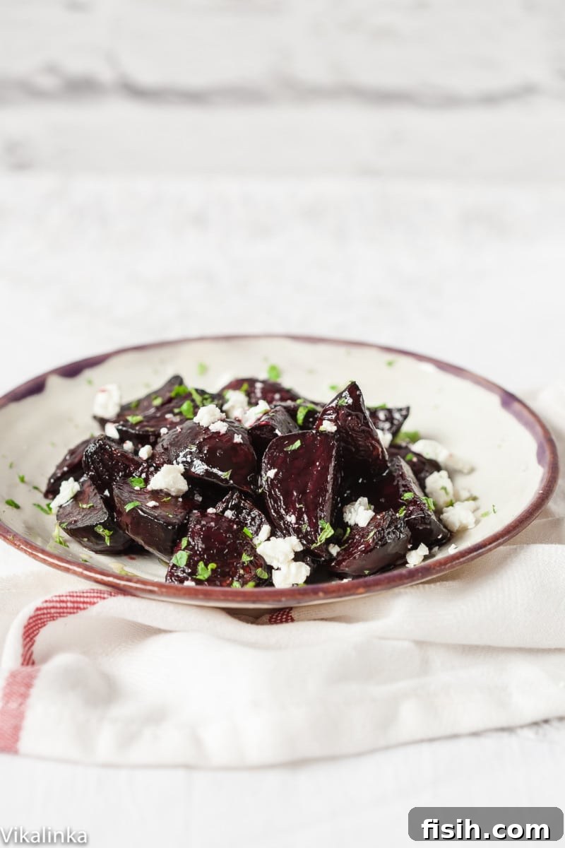 Vibrant beetroot pieces on a white plate, glistening with balsamic glaze and topped with fresh mint and crumbled goat cheese.