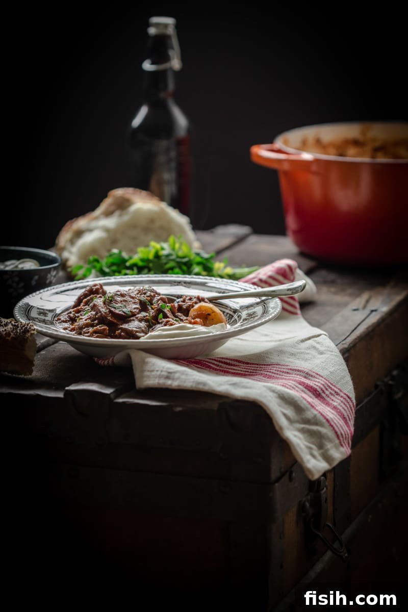 A beautifully presented bowl of Russian Solyanka beef stew, adorned with sour cream and dill, set on a rustic wooden table amidst other culinary elements, creating an inviting meal scene.