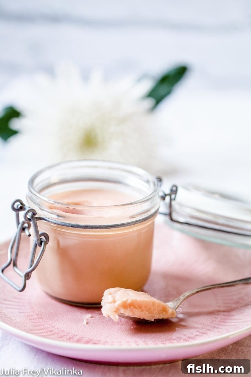 Rhubarb curd in a glass container with a spoon, highlighting its creamy texture