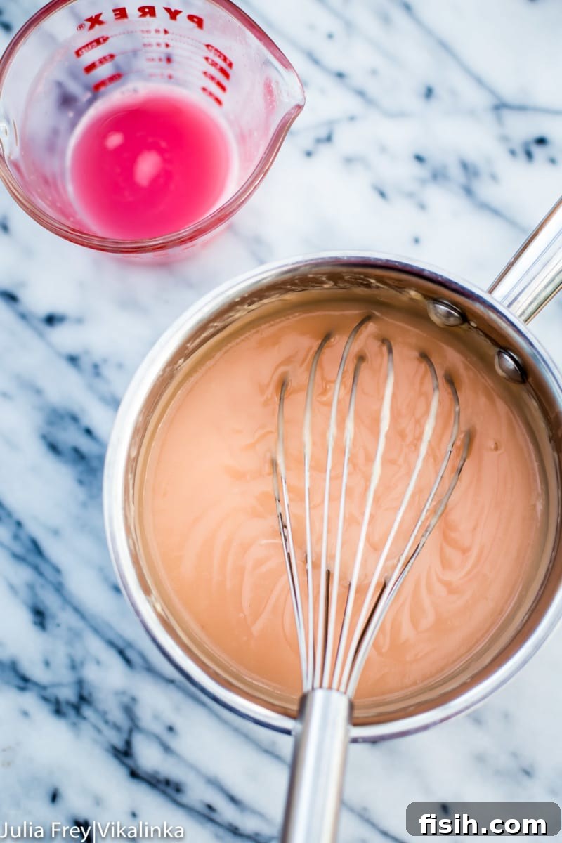 Saucepan with the rhubarb curd mixture being whisked gently over low heat