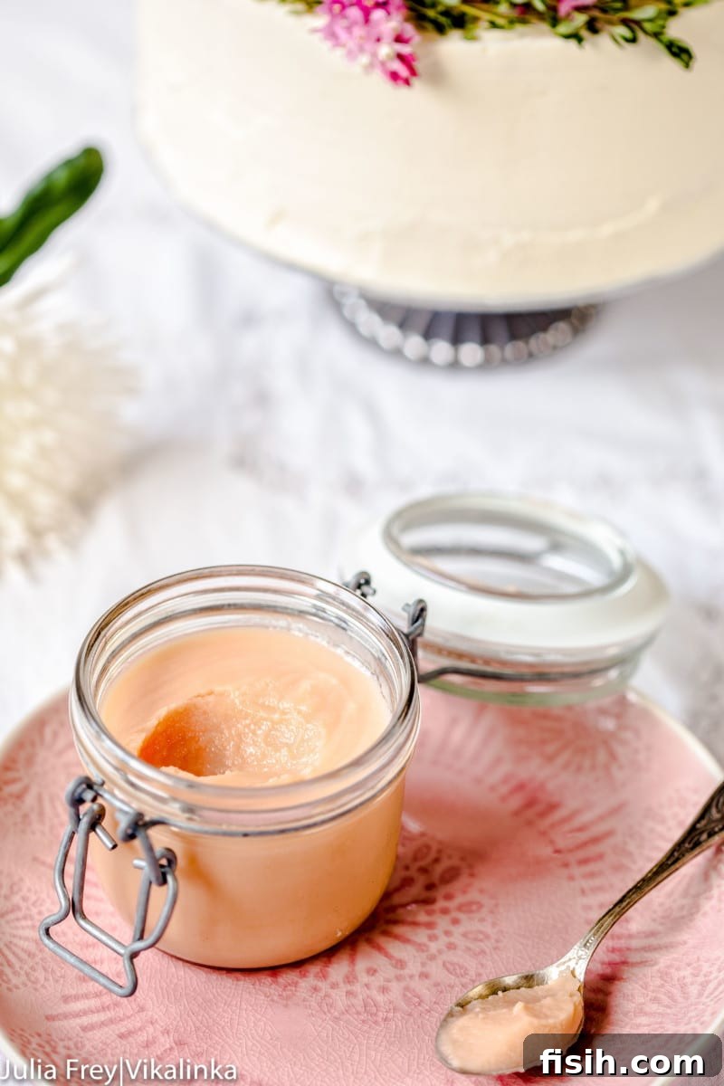 Rhubarb curd in a container on a plate with a spoonful removed, showcasing its rich texture