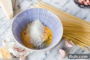 Bowl with cheese and eggs beside spaghetti
