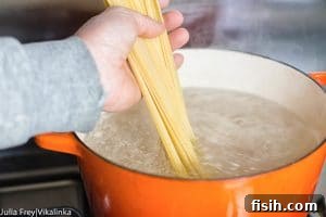 Hand adding spaghetti to boiling water
