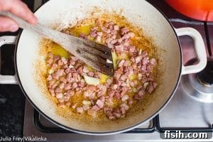 Wooden spatula mixing bacon in pan