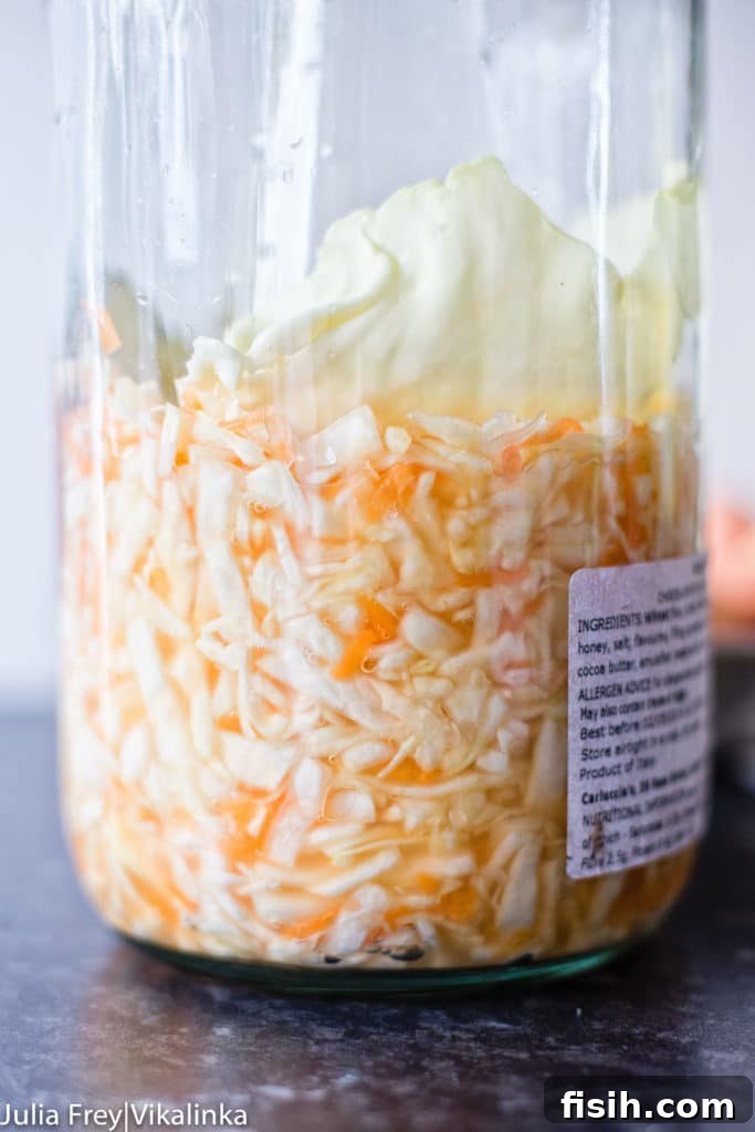 Close-up of homemade sauerkraut in a glass jar, showcasing its vibrant texture