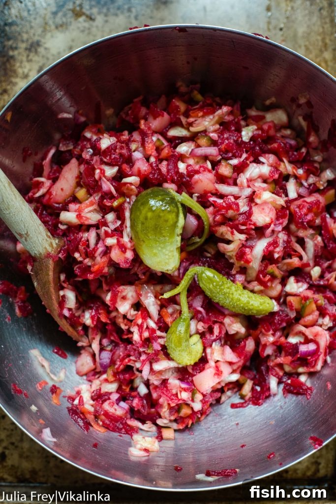 Vibrant beet and sauerkraut salad (Vinegret) in a bowl, garnished with fresh herbs