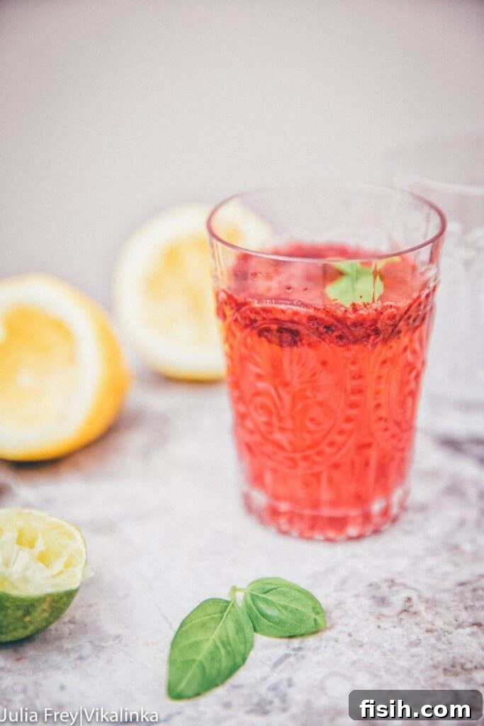 Side view of blackberry basil lemonade in a clear glass
