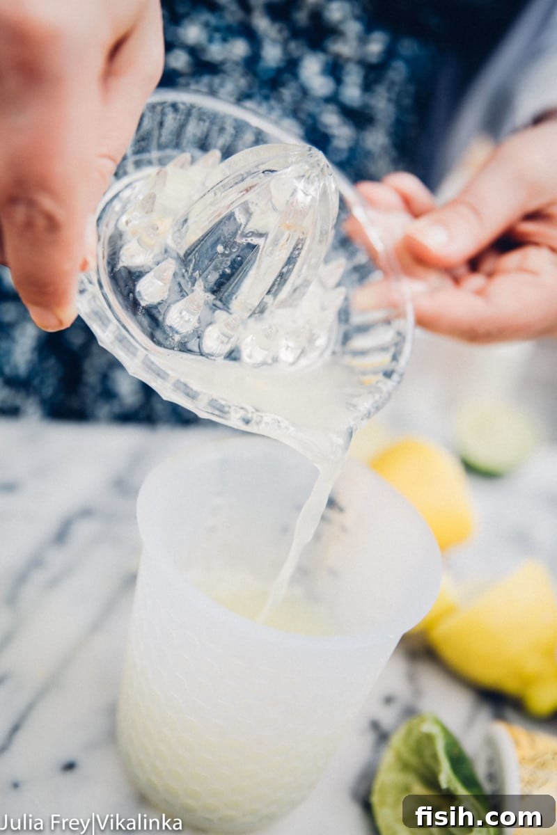 Lemon juice poured from a glass juicer into a measuring cup