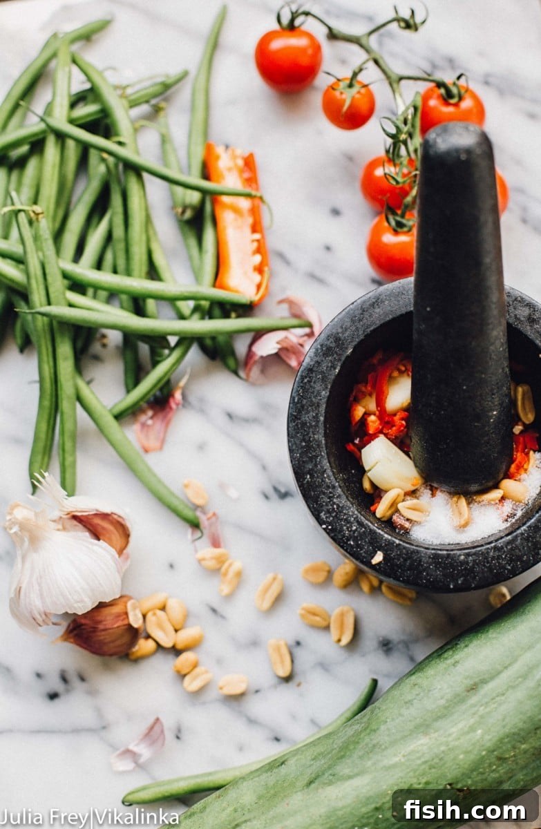 A pestle and mortar grinding fresh ingredients like garlic and chili for a Thai dressing
