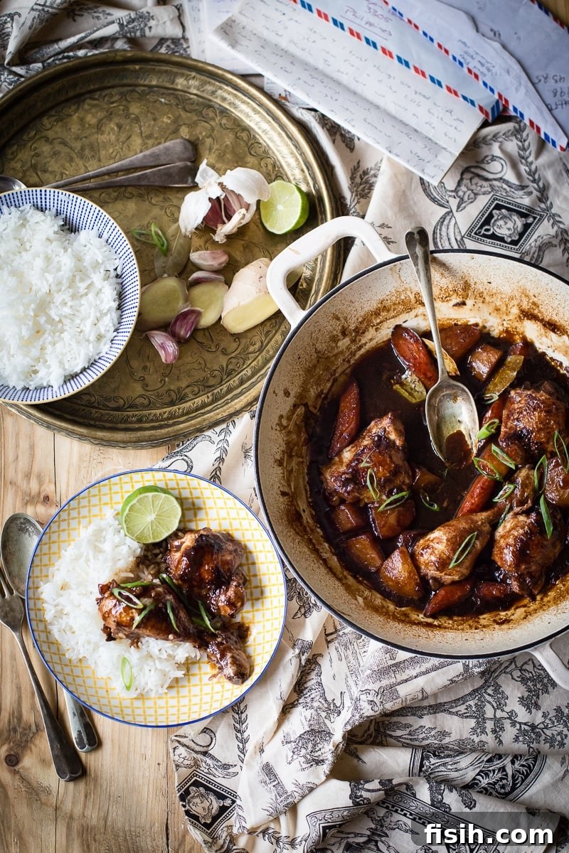 Iconic Filipino Chicken Adobo 3 Table setting featuring a pot of Filipino Chicken Adobo, a plate of adobo with rice, and side dishes.