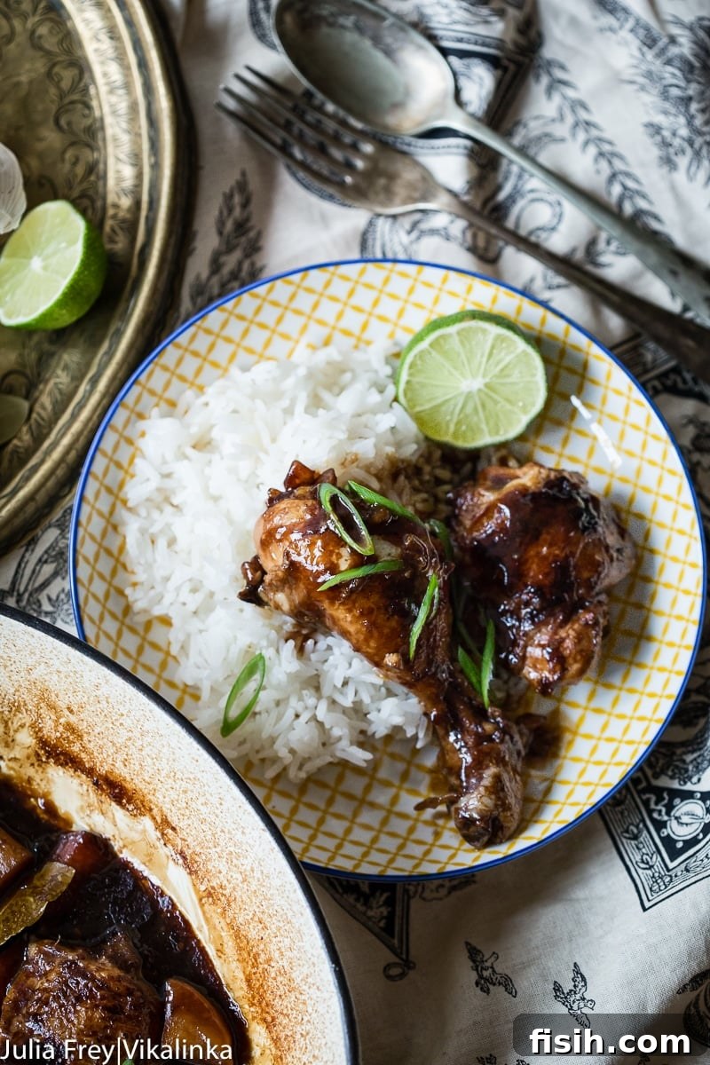 Iconic Filipino Chicken Adobo 4 Plate of rice with Filipino Chicken Adobo on top, accompanied by a lime slice for garnish.