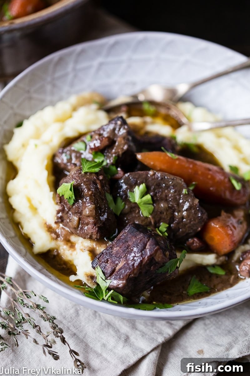 A close-up of a bowl of Beef Bourguignon with creamy mashed potatoes, highlighting the rich texture and color of the stew.