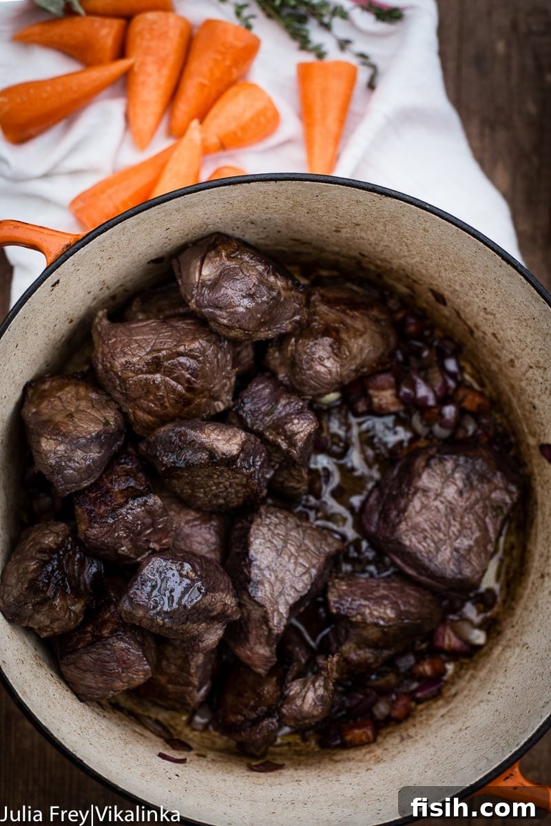 Beef stewing in a heavy cast iron pot, bubbling gently as it cooks, promising deep flavors.