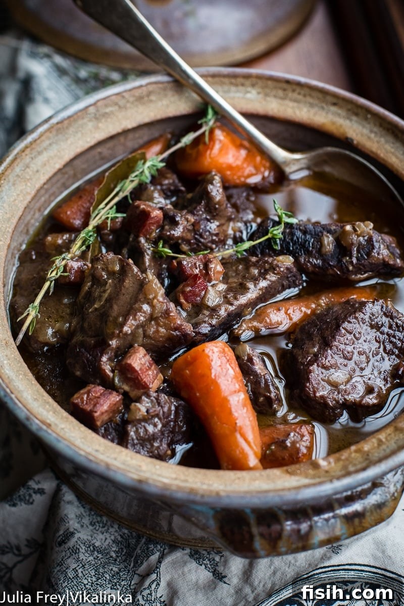 A large serving dish filled with Beef Bourguignon, garnished with fresh parsley, ready to be dished out.