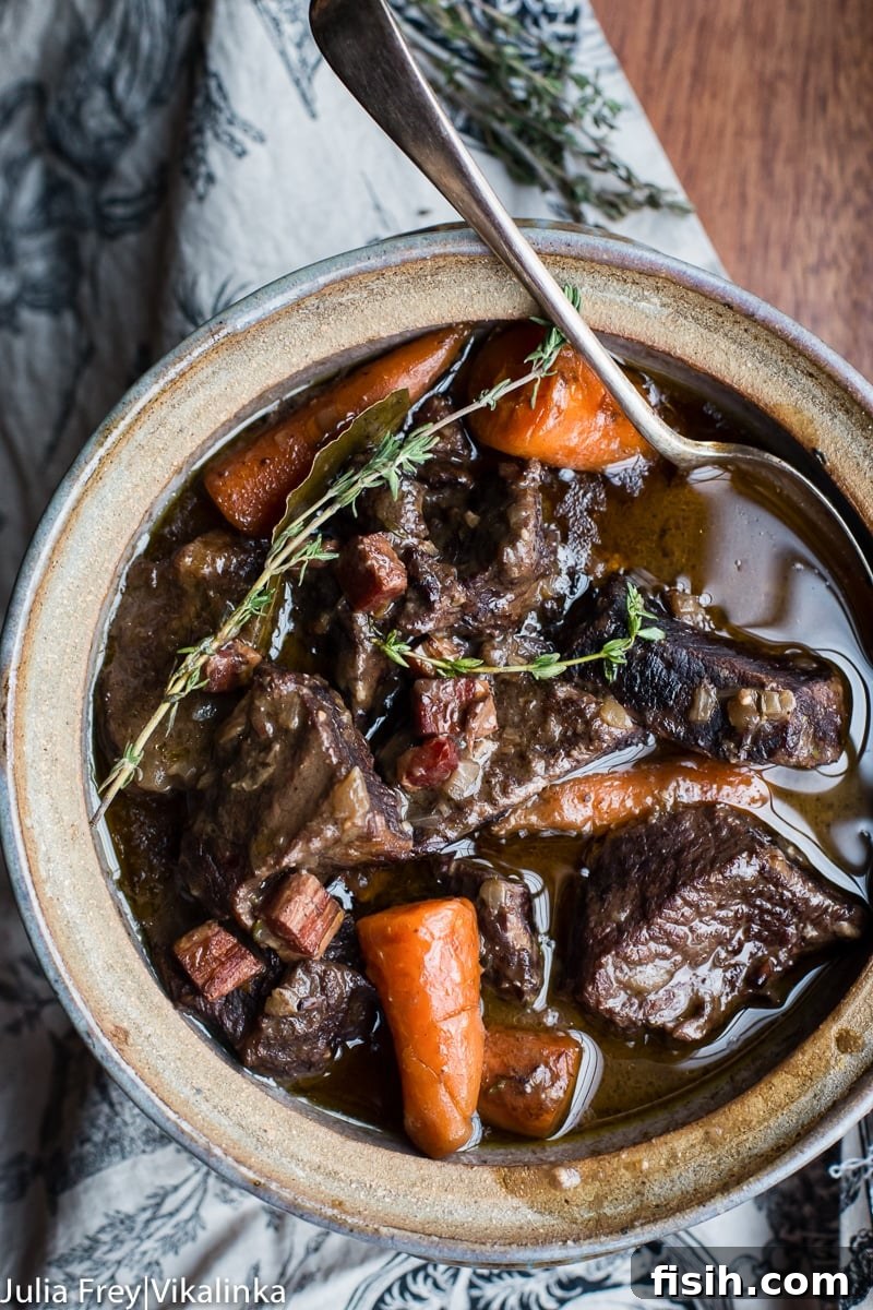 A top-down view of Beef Bourguignon in a rustic serving dish, beautifully presented and garnished.