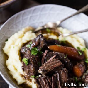 A bowl of Beef Bourguignon on mashed potatoes with cutlery