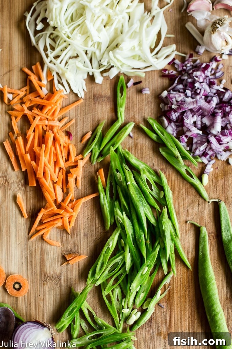Fresh ingredients laid out for Pancit Canton, including sliced carrots, green beans, cabbage, onions, and garlic