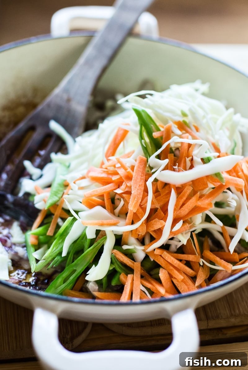 Sliced cabbage, carrots, and green beans in a pan, ready for stir-frying in Pancit Canton