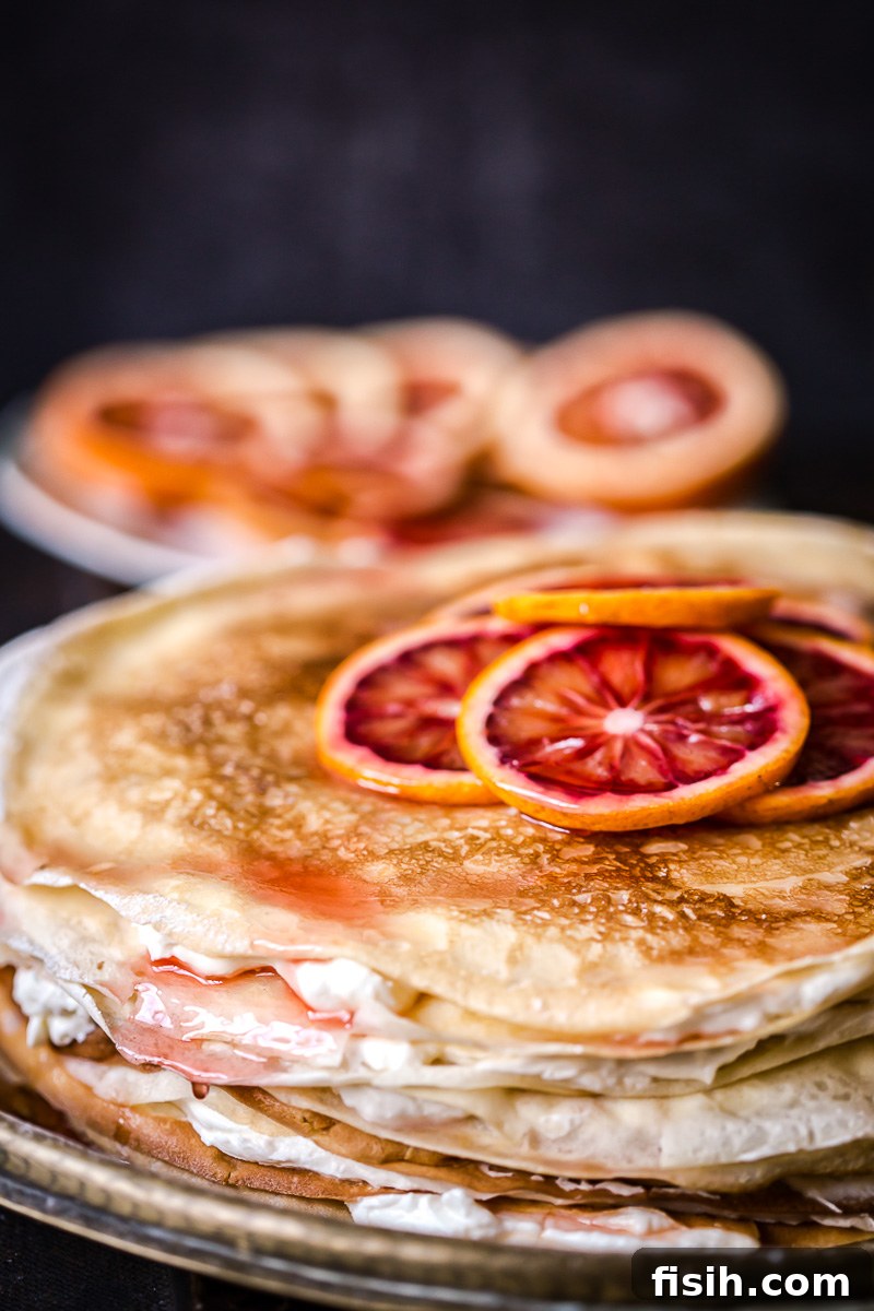 Crepe cake topped with sliced blood oranges, showcasing delicate layers and vibrant colors