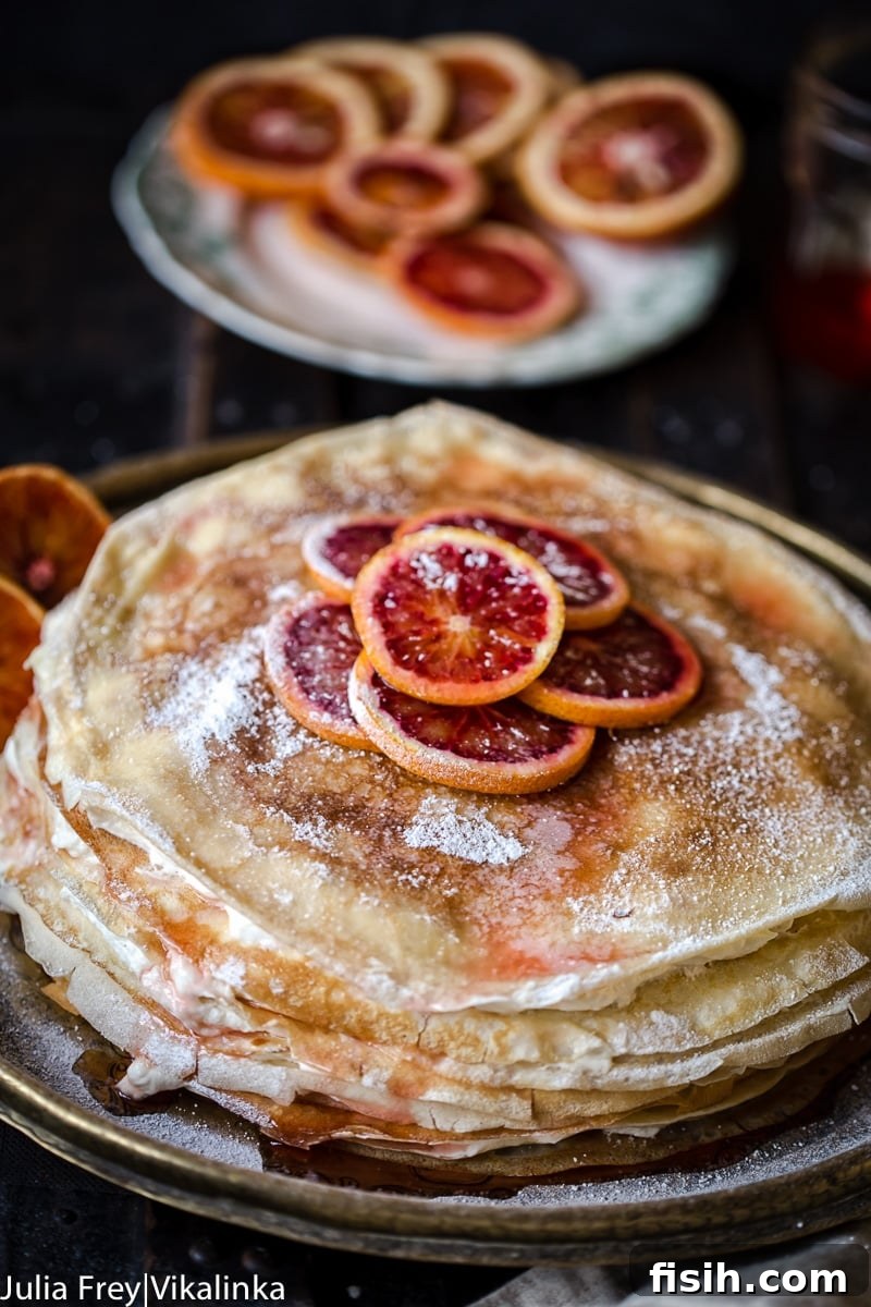 A beautifully sliced crepe cake revealing multiple layers of almond crepes and blood orange ricotta cream