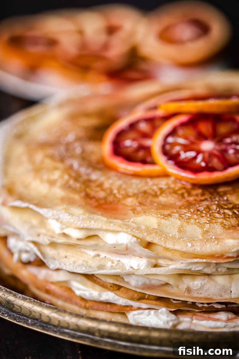 Close-up of a slice of blood orange ricotta crepe cake, showing layers and creamy filling