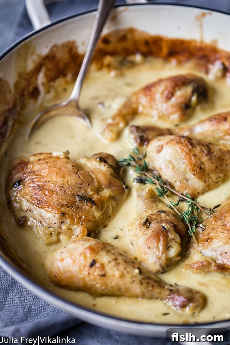 Creamy Wine Mustard Chicken 2 Crispy-skinned chicken in a rich, creamy mustard sauce, garnished with fresh herbs, served in a rustic white pan.