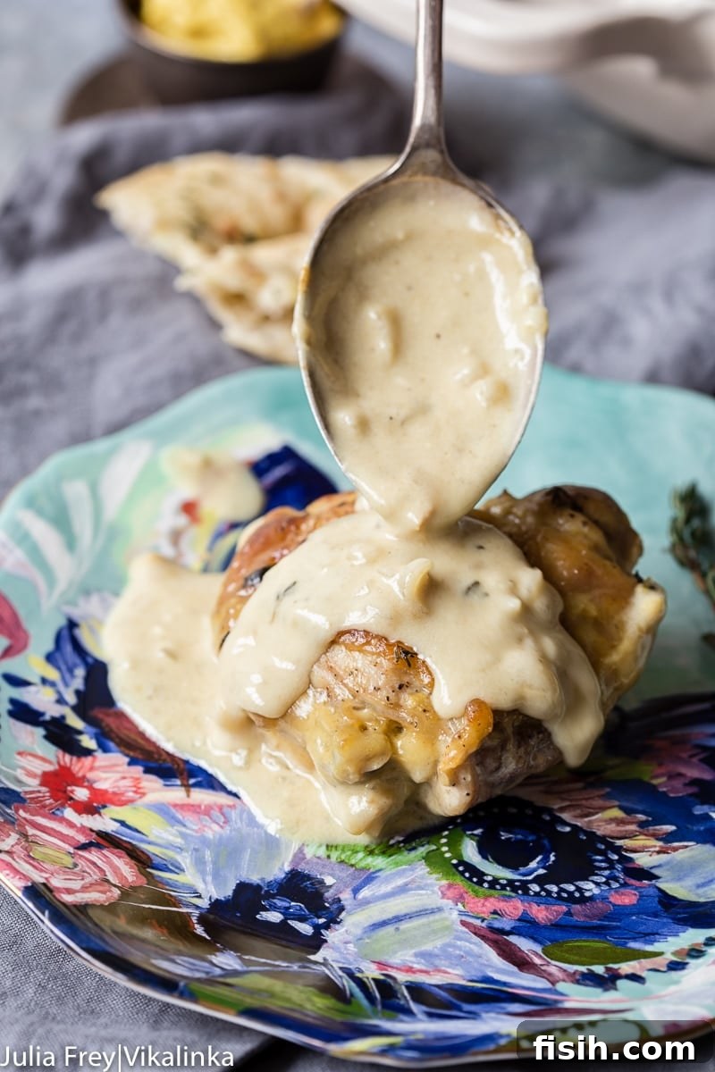 Creamy Wine Mustard Chicken 3 A close-up shot of a fork lifting a piece of tender chicken from a plate, coated in the luscious, creamy mustard sauce.