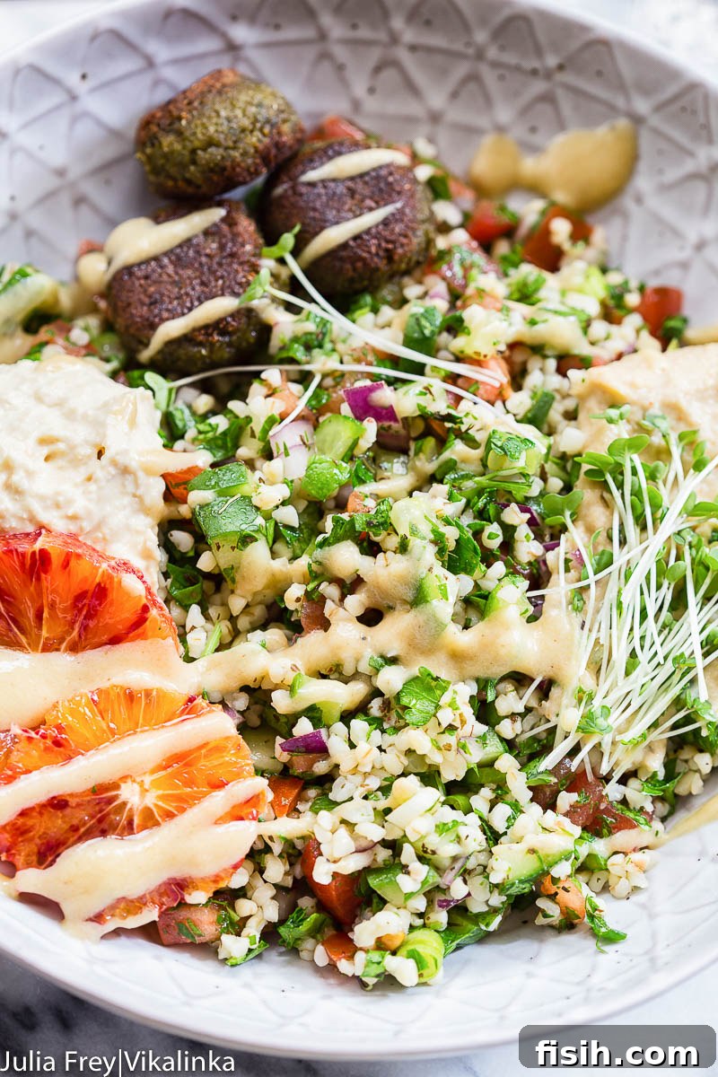 A beautifully arranged falafel salad bowl with tabbouleh, hummus, and golden falafel
