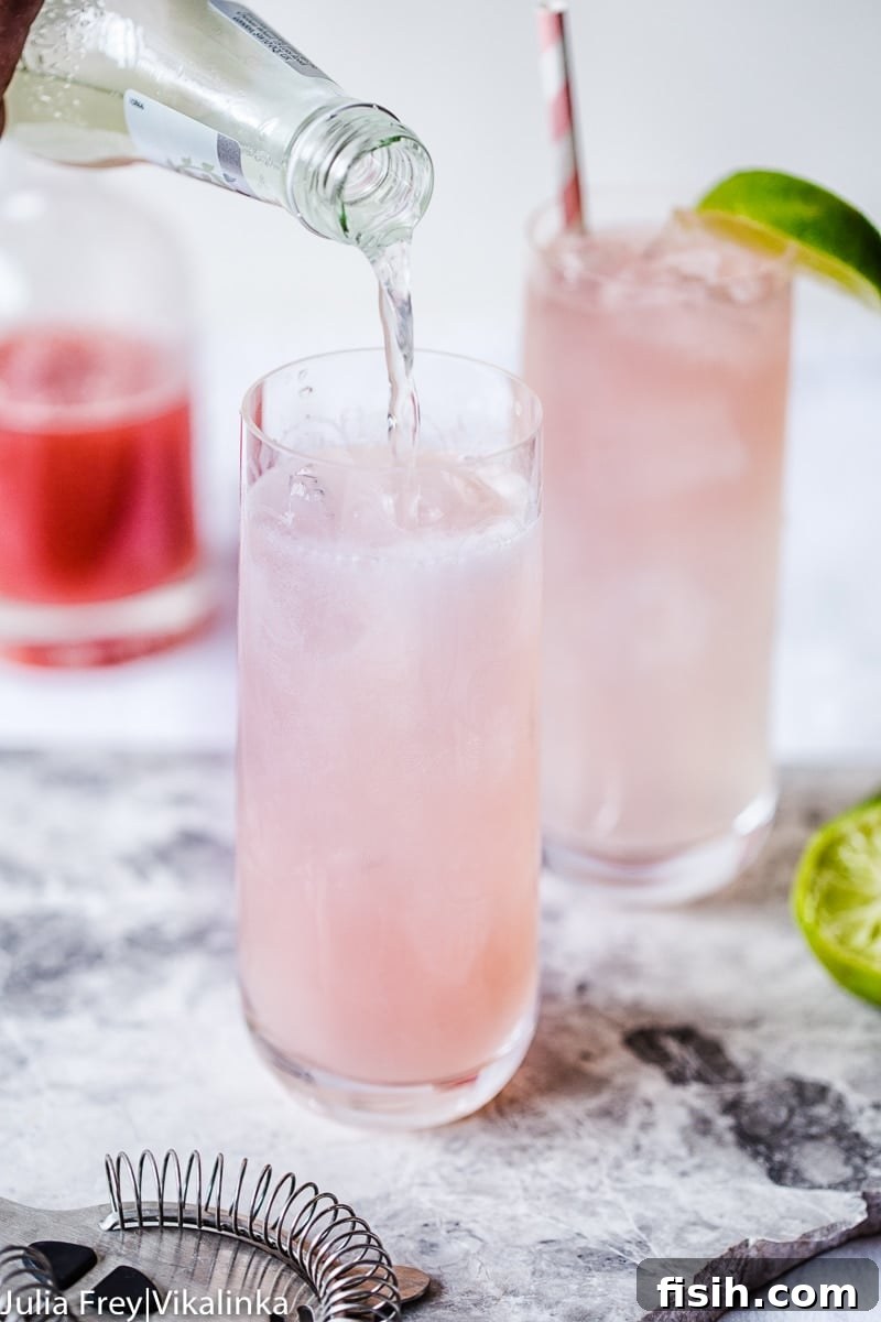 Crimson Rhubarb Mule 4 Rhubarb Moscow Mule in a glass being topped with sparkling drink, showing its beautiful pink hue