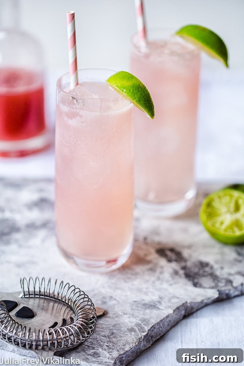 Crimson Rhubarb Mule 5 Rhubarb Moscow Mule in two copper-style glasses on a wooden table, garnished with lime