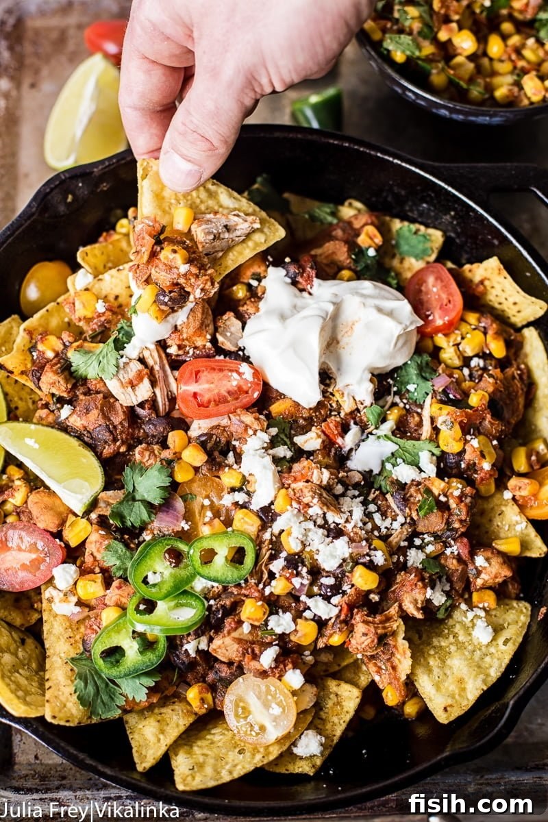 Chicken Chilaquiles with Warm Sweet Corn Salsa 5 Hand pulling nacho from the Chicken Chilaquiles