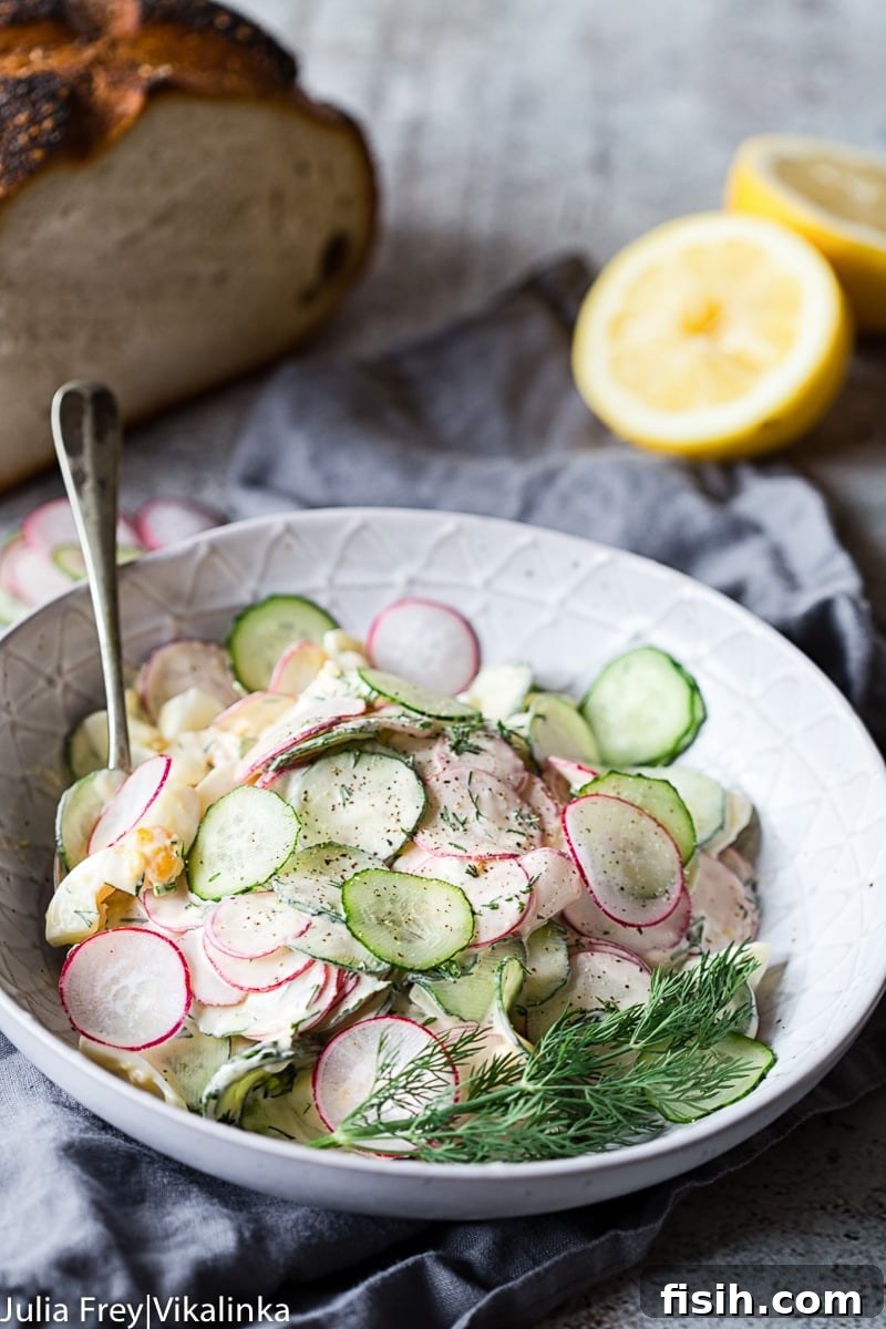 A bowl of creamy dill cucumber, radish, and egg salad, showcasing its fresh ingredients and rich texture.