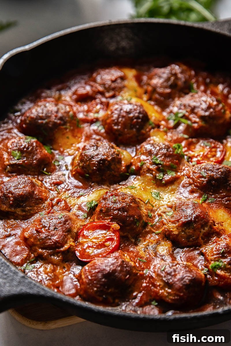 Close-up of baked meatballs with melted mozzarella and fresh arugula