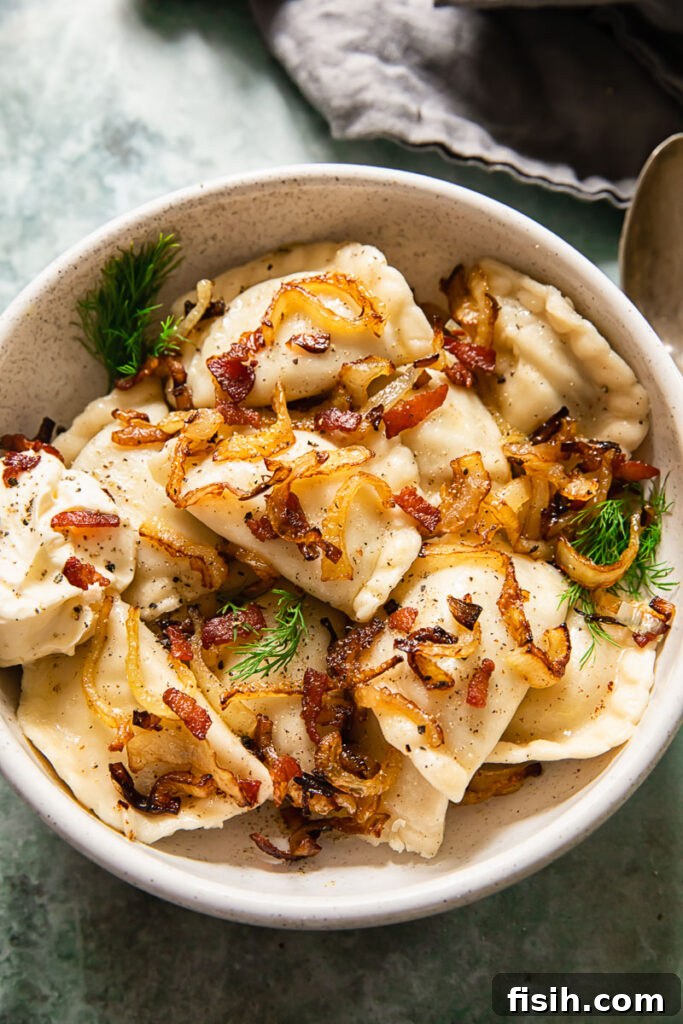 Smoky Bacon and Sweet Onion Potato Pierogi 6 A large bowl brimming with Ukrainian dumplings, generously topped with crispy onions and bacon, served with a side of fresh herbs.